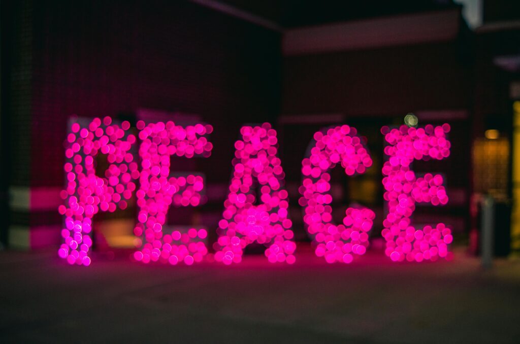 A pink sign that glows and says, "peace".