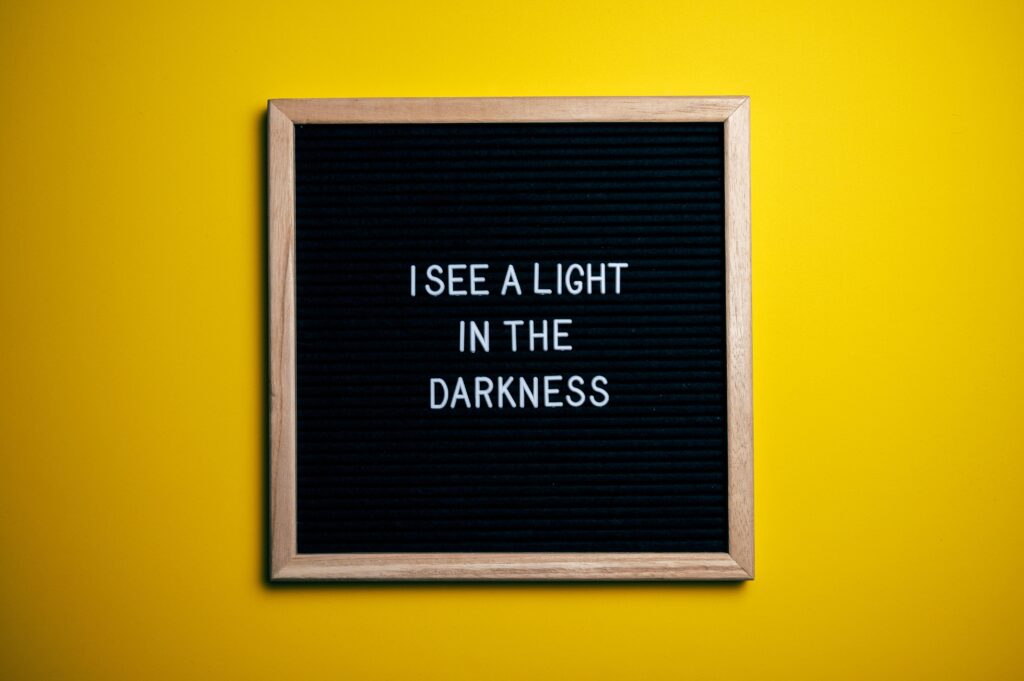 A sign on a black board on a yellow wall.