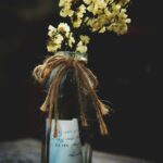 An image of flowers in a bottle with a ribbon and note.