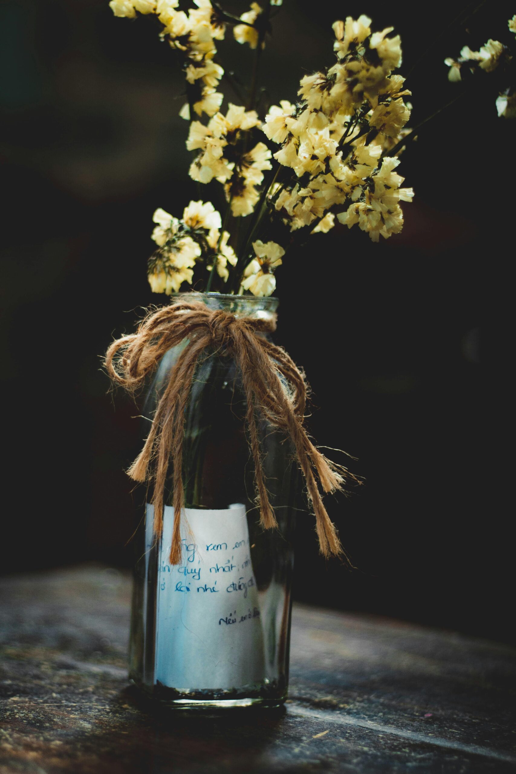 An image of flowers in a bottle with a ribbon and note.