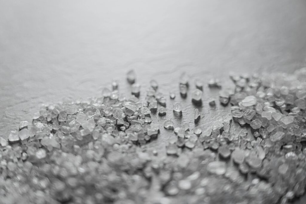 Image of coarse salt scattered on a white surface.